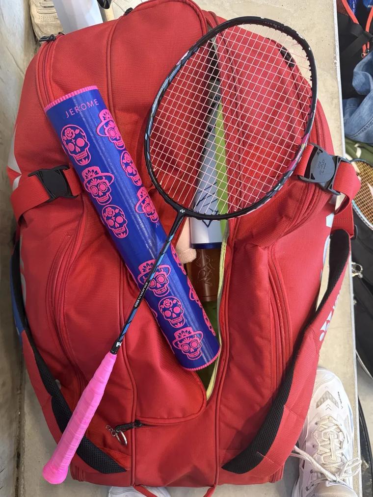 Boîte bleue au prénom JEROME, calaveras roses, posée sur un sac de badminton
